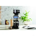 מטחנת קפה Sage Smart Grinder Pro SCG820 בנירוסטה מוברשת על שיש מטבח, טוחנת אל מיכל הקפה הטחון לצד שקית פולים