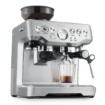 מכונת אספרסו Sage Barista Express (Breville) SES875 נירוסטה במבט תלת רבעי, מוזגת אספרסו לכוס זכוכית