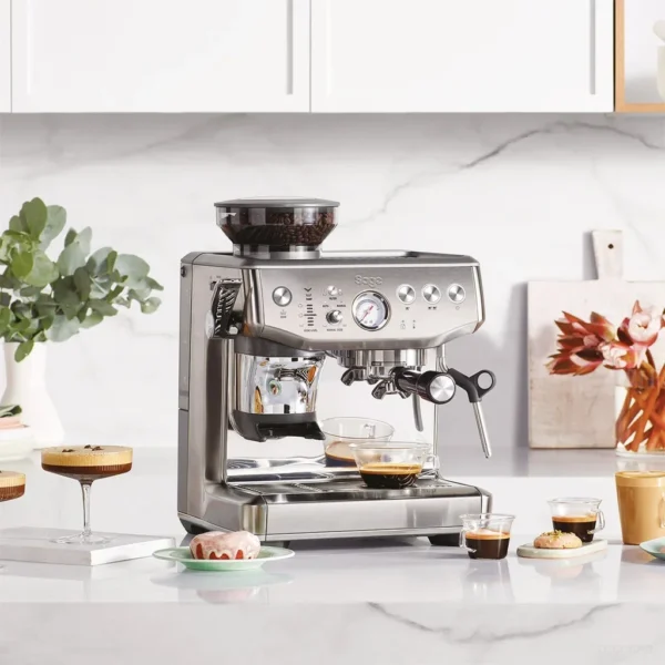 מכונת אספרסו Sage Barista Express Impress SES876 במטבח לבן, לצד מבחר משקאות קפה
