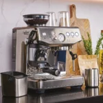 מכונת אספרסו Sage Barista Express Impress SES876 עם מיכל ריקון וכד הקצפה מנירוסטה על השיש