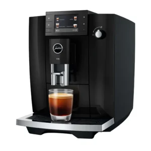מכונת קפה אוטומטית Jura E6 דור 4 Piano Black, מבט תלת רבעי על רקע לבן עם כוס אספרסו