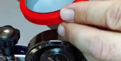 מסננת ראש Matrix של IMS מוחזקת בתוך אטם הראש מעל ראש E61 פתוח של מכונת אספרסו
